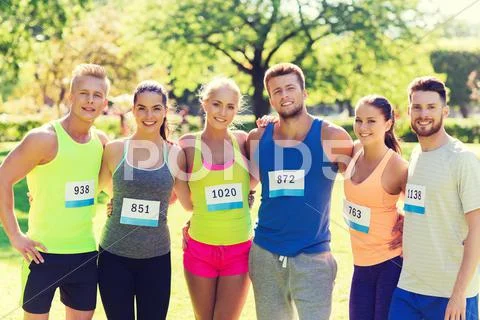 Happy friends or couple with racing badge numbers Stock Photos