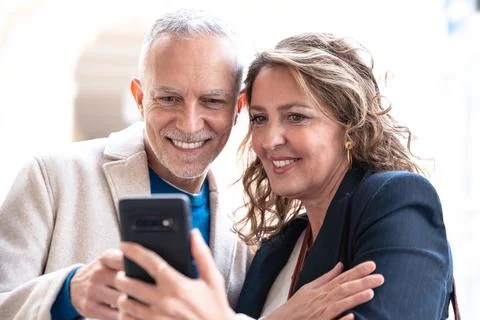 Happy friends or couples using an app on the smartphone outdoors. Stock Photos