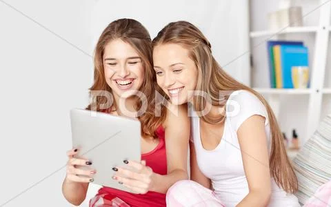 Happy friends or teen girls with tablet pc at home Stock Photos