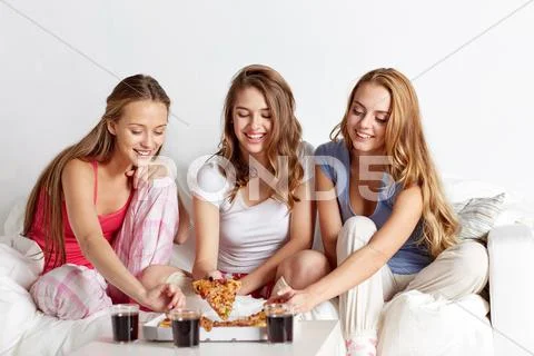Happy friends or teen girls eating pizza at home Stock Photos
