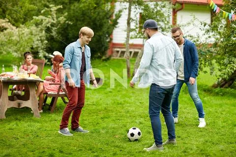 Happy friends playing football at summer garden Stock Photos