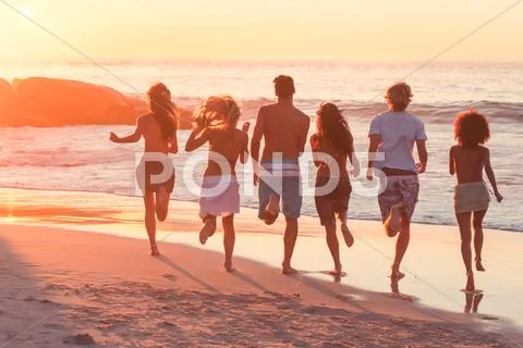 Happy friends running to the sea Stock Photos