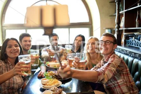 Happy friends with selfie stick at bar or pub Stock Photos