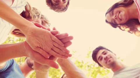 Happy friends stacking hands together in the park Stock Footage