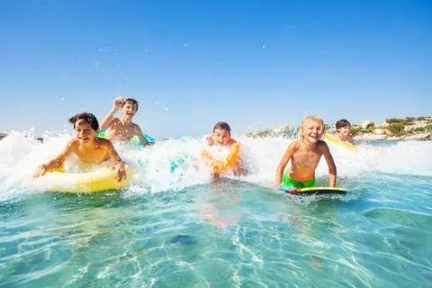 Happy friends swimming in the sea on body boards Stock Photos