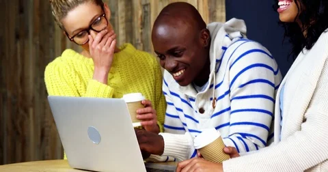 Happy friends using laptop while having coffee Stock Footage