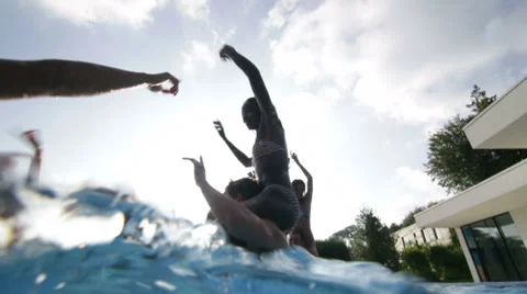 Happy fun loving group of friends playing in the water at summer pool party Stock Footage