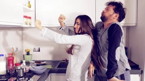 Happy funny crazy couple dancing in kitchen in pajamas slow motion Stock Footage