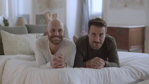 Happy gays lying on bed in morning and looking at camera Video stock 229631253