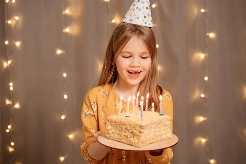 Happy girl with birthday cake. tradition to make wish and blow out fire Stock Photos