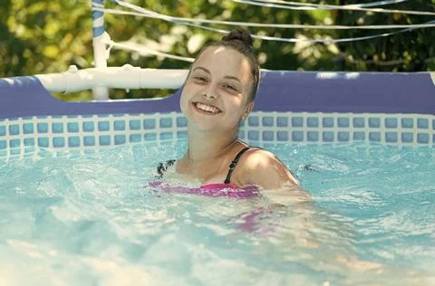 Happy girl child enjoy swimming in leisure pool on sunny summer day, vacation Stock Photos