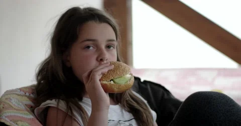 Happy Girl Eats Big Appetizing Hamburger at Veranda Stock Footage 64746926