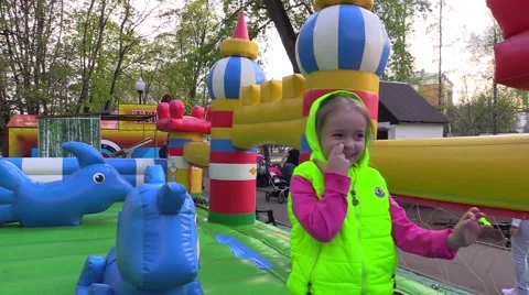 Happy girl is going to play on inflatable trampoline in the children's amusement Stock Footage 68441353