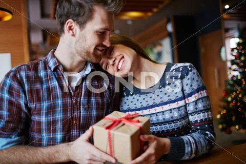 Happy girl keeping her head on shoulder of her boyfriend while sitting in cafe Stock Photos