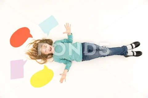 The happy girl lay on the floor near the dialog signs. View from above Stock Photos