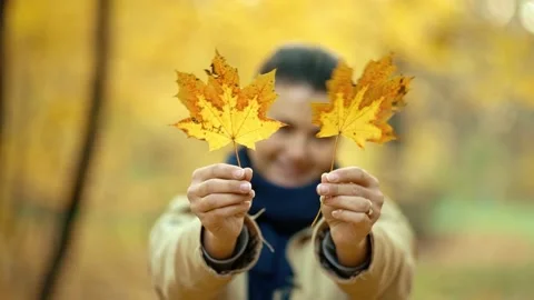 Happy girl making funny faces covering herself with autumn leaves. Video stock 231069698