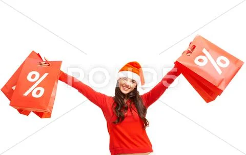 Happy girl in santa cap holds red paperbags with symbol of sale Stock Photos