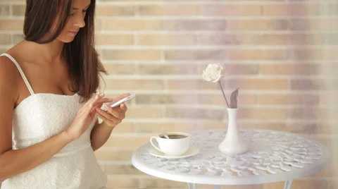 Happy girl sitting at cafe using mobile phone looking at camera and smiling.  Видео 34196785