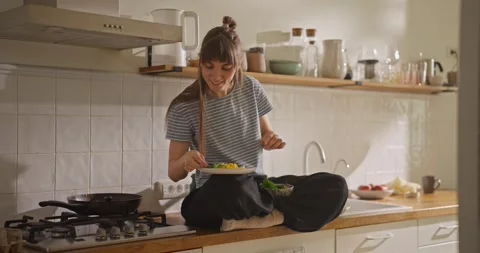 Happy girl sitting on kitchen table and making breakfast presentation for Stock Footage 318079964