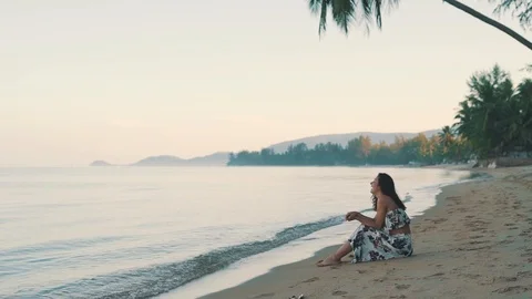 Happy girl sitting on the sand by the ocean Stock Footage 110188853