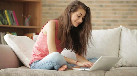 Happy girl sitting on sofa using laptop looking at camera and smiling Video stock 35533288