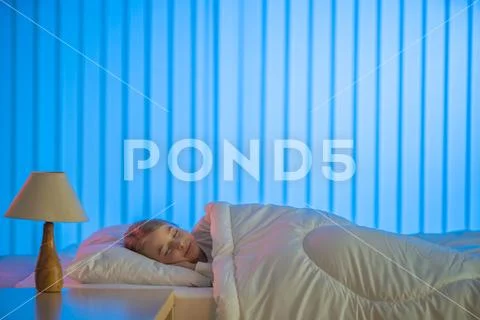 The happy girl sleeping on the bed. Evening night time Stock Photos
