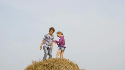 Happy girl standing on hay stack at harvesting field in countryside. Cheerful Vidéo 114986284