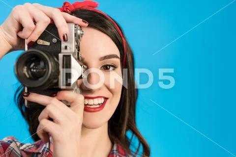 The happy girl takes a photo with an retro camera on the blue background Stock Photos
