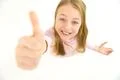 The happy girl thumbs up to the camera. View from above Photo