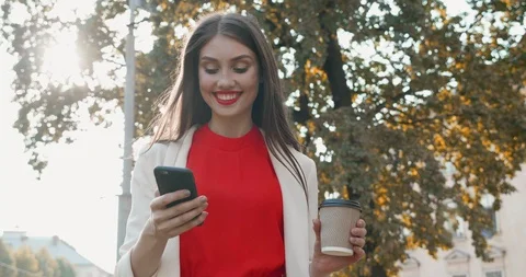 Happy Girl typing a Message while Walking Wind waving her Long straight Brown Stock Footage 125166949