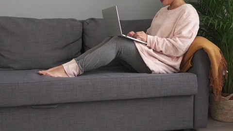 Happy girl using laptop while sitting on modern couch at home Video stock 97573754