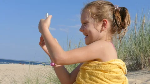 Happy, girl is using smartphone on a sandy beach Stock Footage