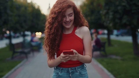 Happy girl using smartphone while walking down the alley and cheerfully laughing Stock Footage 115669915