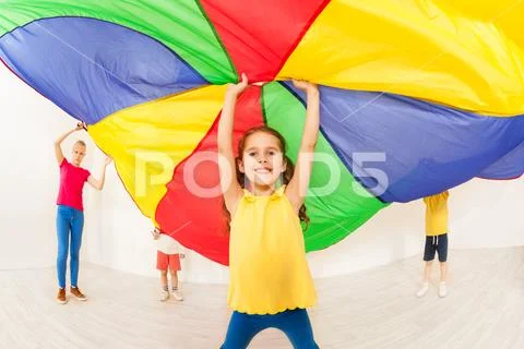 Happy girl waving parachute during sports festival Stock Photos