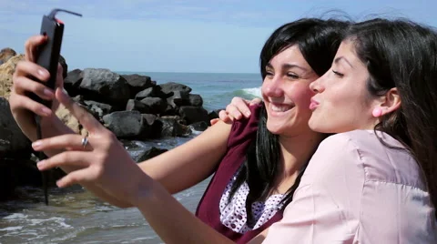 Happy girlfriends taking selfie with cell phone in front of ocean closeup Stock Footage 60382962