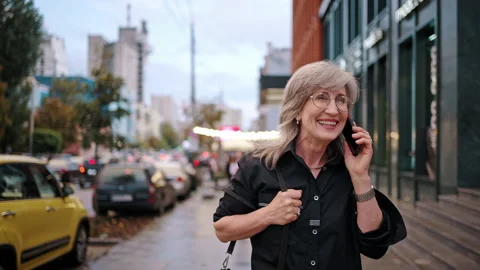Happy good looking business woman walking along the city street and talking on Stock Footage