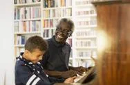 Happy Grandfather And Grandson Playing Piano Stock Photos