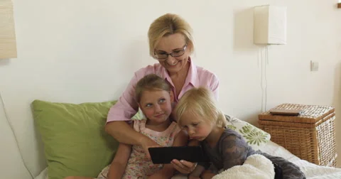 Happy grandmother with kids playing games on tablet at home Stock Footage