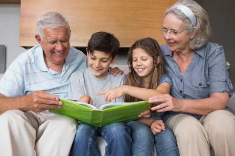 Happy grandparents and grandkids looking at album photo Stock Photos