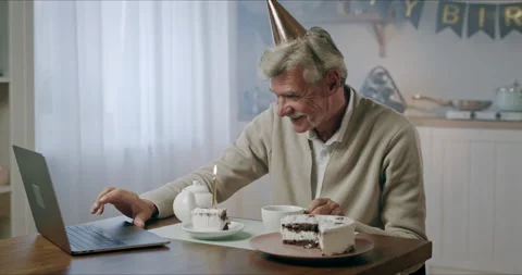 Happy gray haired elderly man grandfather in party hat celebrates birthday alone Video stock 139528872