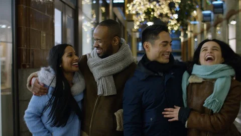 Happy group of diverse young couples walking the street at Christmas, in slow mo Видео 100361693
