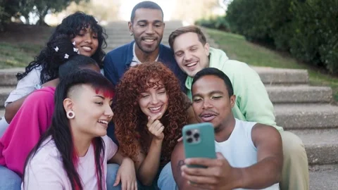 Happy group of friends using mobile smartphone sitting outside of college - Video stock 335264279