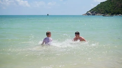 Happy guy and kid play makes splashes in the sea Vidéo 74885557