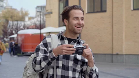 Happy guy with backpack standing at the street and taking different pictures. Stock Footage 163605264