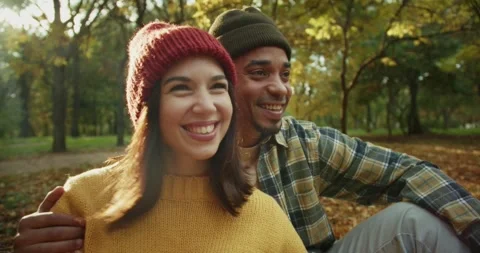 A happy guy with Black skin in a checkered shirt hugs his girlfriend in a hat Stock Footage 299924313