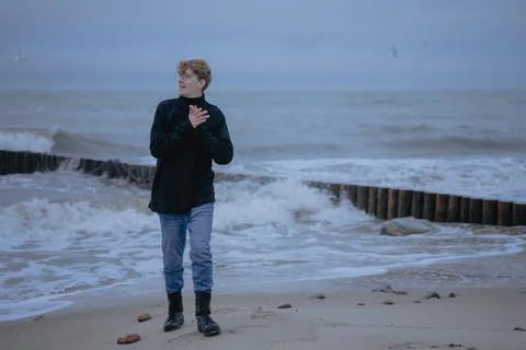 Happy guy in a black sweater on the background of the sea looks to the side Stock Photos