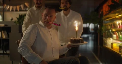 Happy guy in business clothes and a white shirt holds a cake with a candle in Stock Footage 313272453