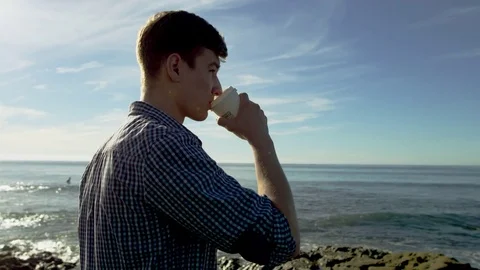 Happy guy with a cup of coffee on a beach Stock Footage 75751716