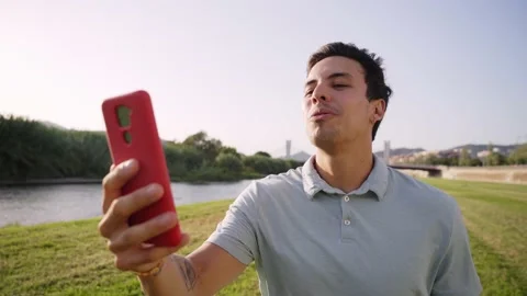 Happy guy enjoying video conversation outside. Young man in casual clothes Stock Footage 238407627