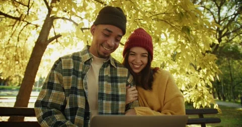 A happy guy in a hat and a plaid shirt sits on a bench with his girlfriend and Stock Footage 299924057